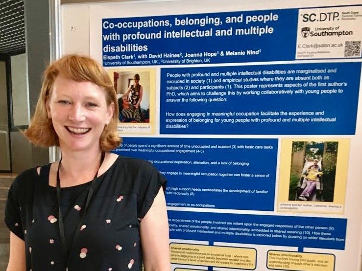 A woman stood in front of a blue poster with text and images
