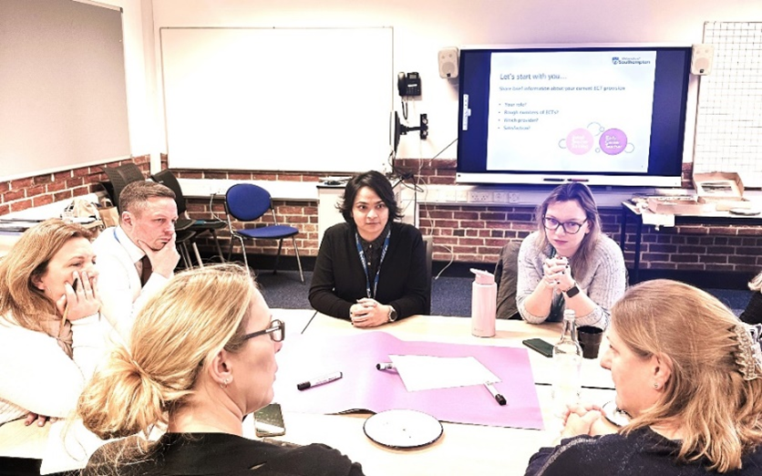A group of 6 people sat around a table, engaged in a discussion.