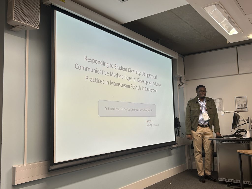 A man standing in front of the projected screen, with the title of the presentation. 