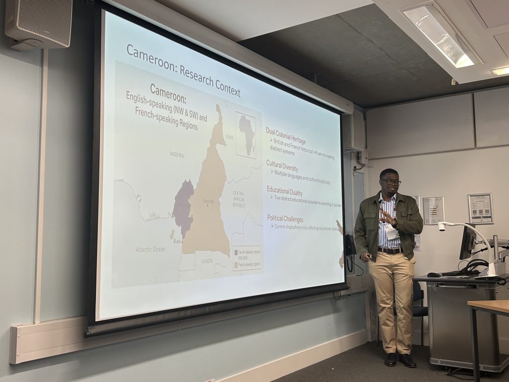A man standing in front of the projected screen, pointing to the map of Cameroon.